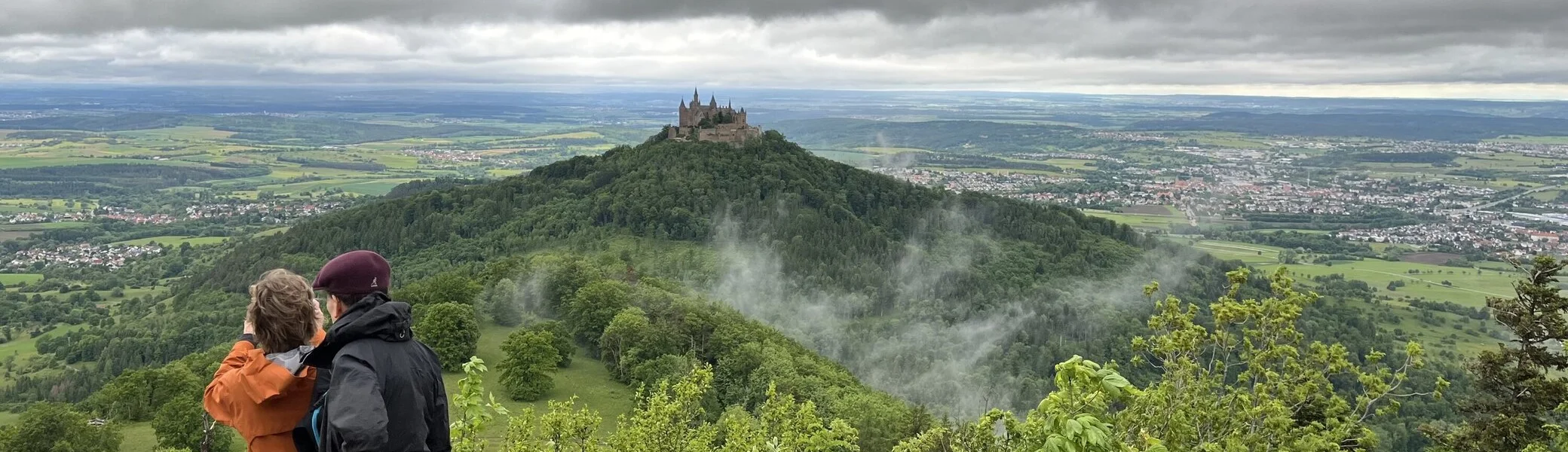 Zwei Wanderer blicken aus der Ferne auf die Zollernburg | © Claudia Endriss